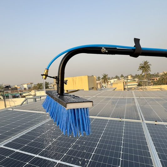 A solar panel cleaning brush with a blue bristle head being used on a solar panel array.
