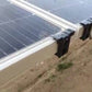 Two dark gray solar clips attached to two separate solar panels, securing them in place.