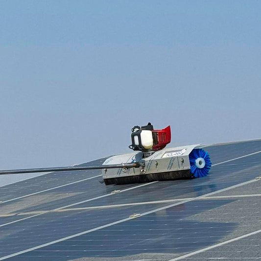 A solar panel cleaning robot with a red and silver body and blue brushes, moving along a solar panel.