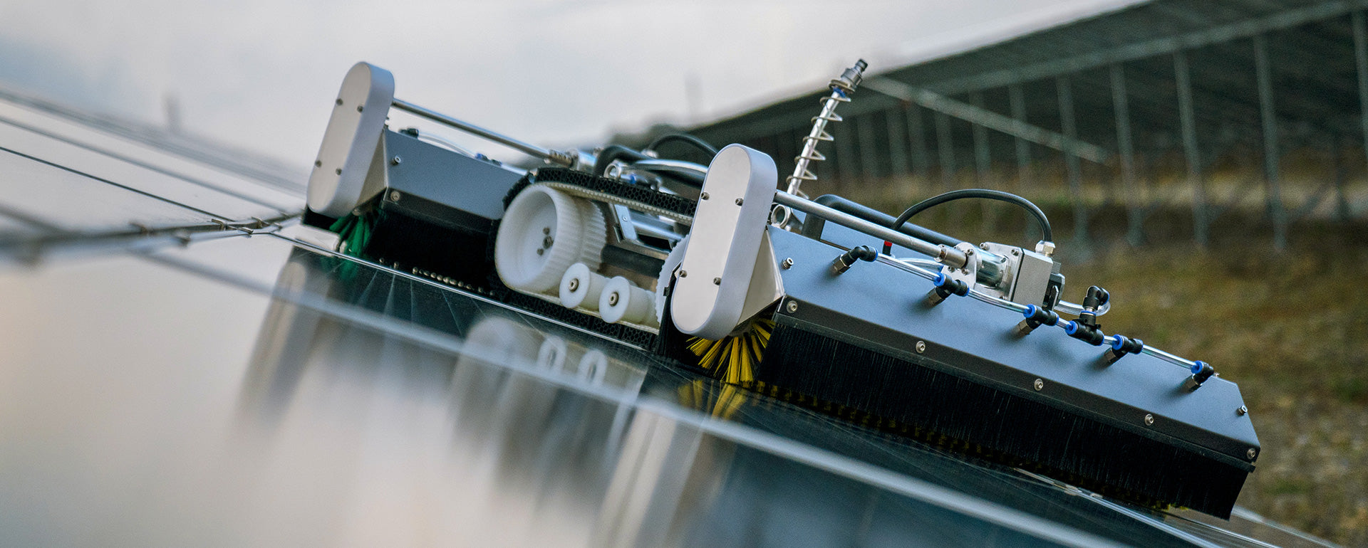 Diagonal view of the PVCARE M1 mini solar panel cleaning robot with caterpillar tracks and brush assembly positioned on solar panels