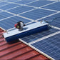 Silver steel solar cleaning robot with blue rotating brush cleaning solar panels on a red-colored rooftop