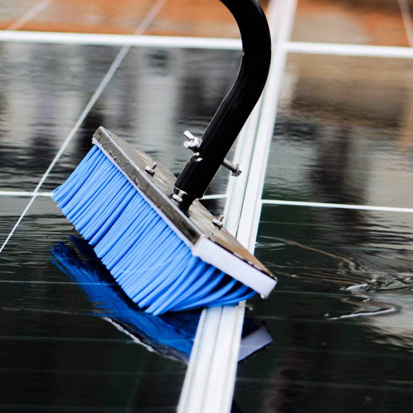 Solar Cleaning tool with blue bristle brush cleaning a glass surface.