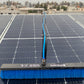 Solar panel with a cleaning brush on a rooftop with buildings in the background