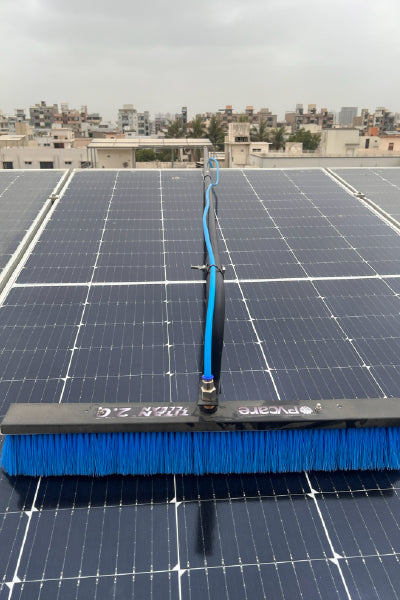 Solar panel with a cleaning brush on a rooftop with buildings in the background